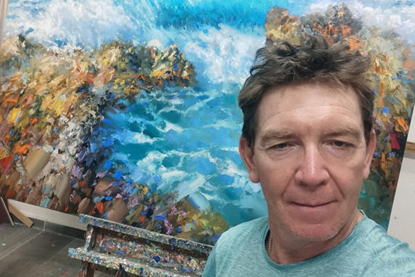 Artist Dmitry Spiros with painting Caribbean coastline at sunrise